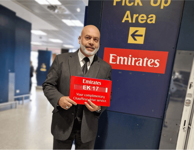 SCS Chauffeurs driver holding an Emirates meet and greet sign in the pick-up area of an airport